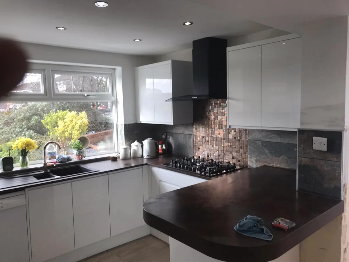 Completed kitchen with dark worktops and white cabinetry