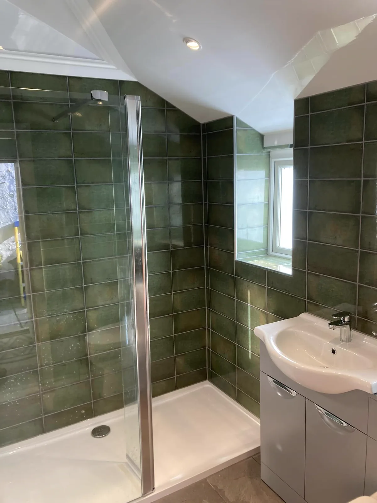 Green tiled shower room with fitted vanity